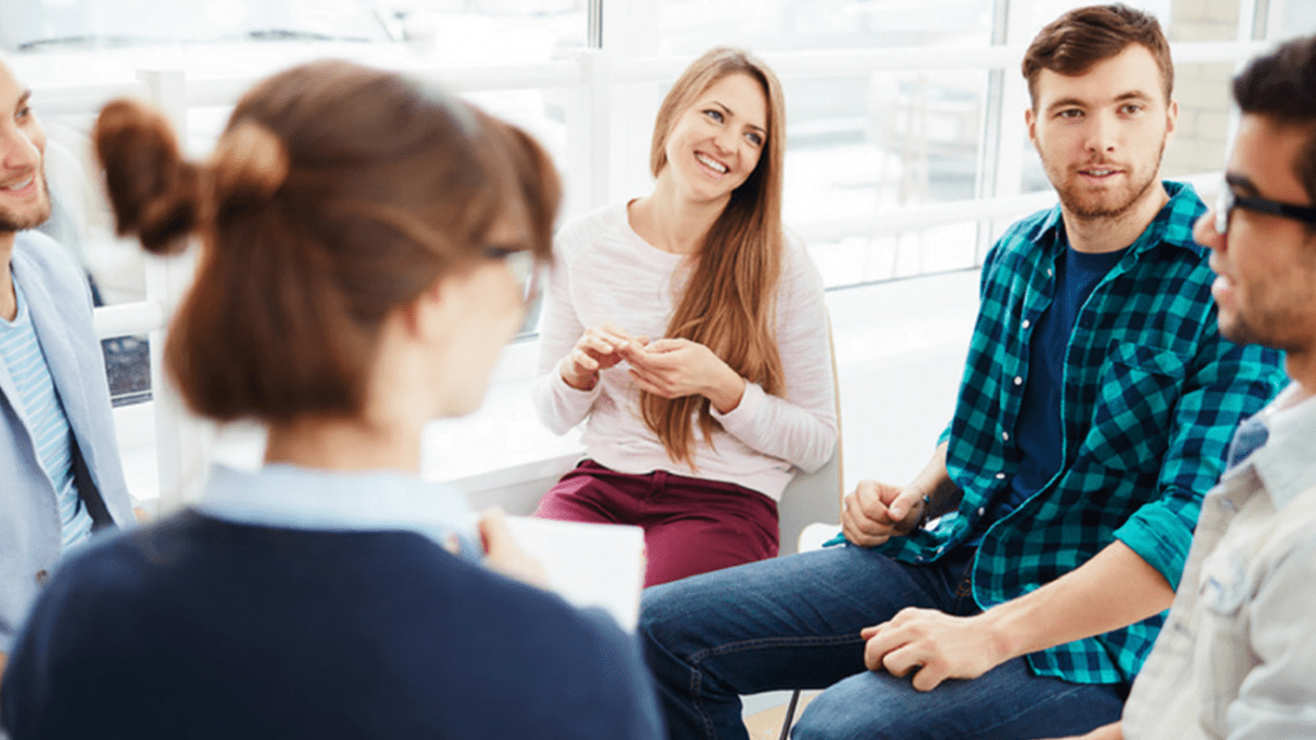 A group of people sitting in a room talking to each other