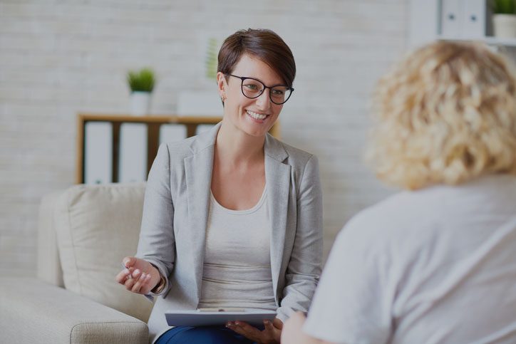 A woman sitting on the couch talking to another person.