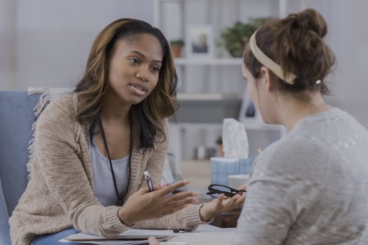 A woman sitting at a table talking to another person.