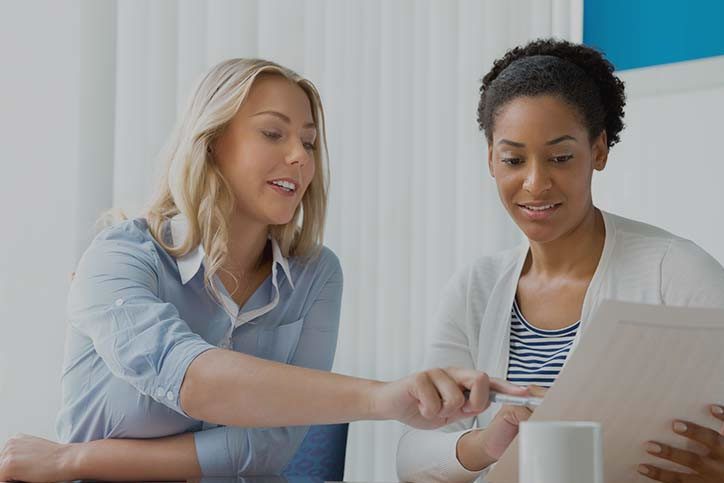 Two women are looking at a laptop together.